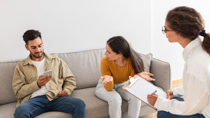 Couple consulting with counselor, man using phone