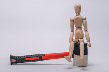 a wooden man sits on a white-black-red rubber mallet