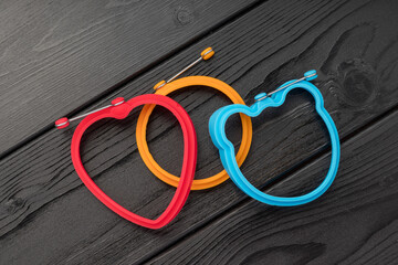 Two silicone bracelets, one red heart-shaped and one orange circular, on a dark background