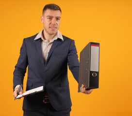 Businessman in suit carrying a binder, gesturing with his hand, on an orange background, appears to be explaining something.
