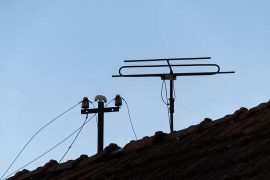 an old antenna for receiving television and radio broadcasts on the roof of an old house and an old connection to a wired radio