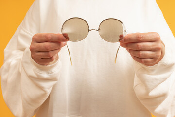 A pair of hands holding round wire-frame glasses.
