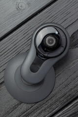 A black spherical webcam with a stand on a wooden surface.