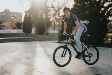 Casual, active man riding a bicycle in a sunny park setting, enjoying the outdoors and leisure time.