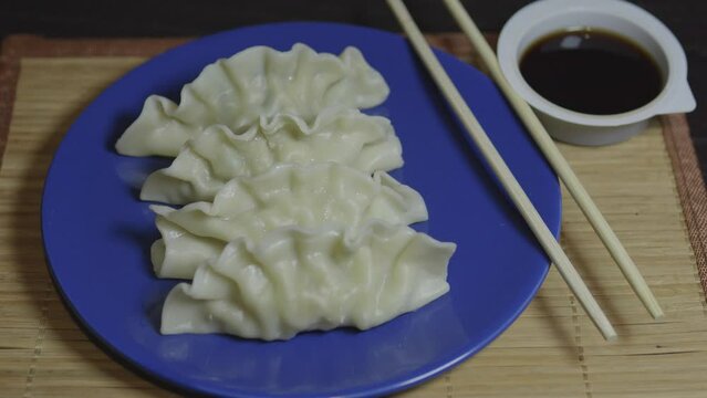 Dumplings gyoza mandu on a blue plate with wooden chopsticks.