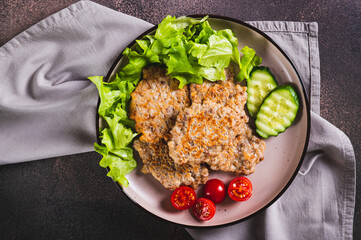 Close up of spicy buckwheat pancakes with slices of cucumber, tomato and lettuce on a plate top view