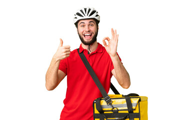 Young delivery man with thermal backpack over isolated chroma key background showing ok sign and...