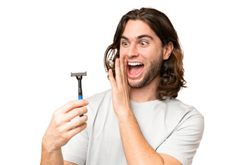 Young handsome man shaving his beard over isolated background with surprise and shocked facial...