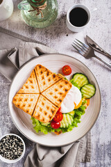 Poached egg with cucumber, tomato and lettuce on waffle toast on a plate top and vertical view