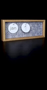 Portrait footage of a wooden calendar block showing the date January 16th which is Martin Luther King Day with a mans hand putting on and taking off the metal discs with the date and month on them