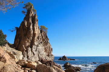 Fototapeta na wymiar Una roca puntiaguda en una cala en la costa mediterránea