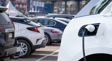 Close-up of a charging electric car on the background of parked cars.
