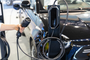 Woman holding plug of electric car charging station