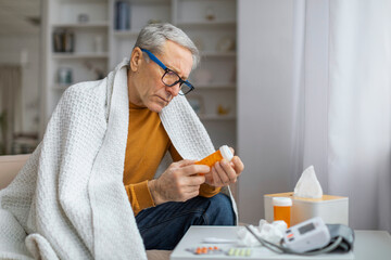 Senior man with medications examining pill bottle