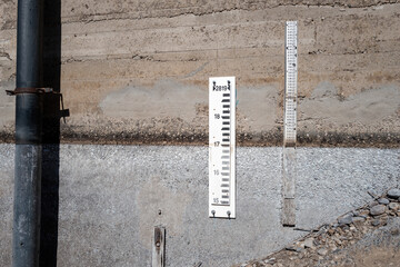 Water level gages on the cement walk of a diversion dam - obrazy, fototapety, plakaty