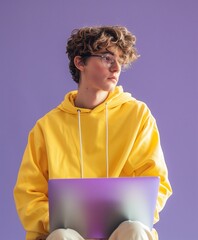 Un joven contemplativo, envuelto en una sudadera amarilla, se sienta con un portátil, el emblema de una generación digital, su mirada reflexiva insinúa el mundo de posibilidades online.