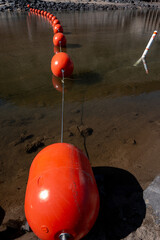 Bright orange buoy in the water behind a dam