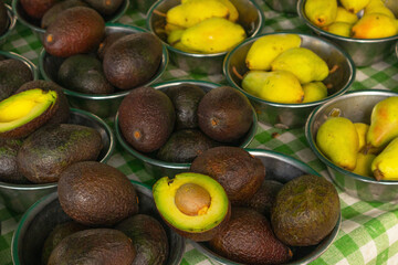 avocados and pears in metallic bowls in market, food background