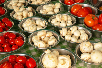 mushrooms and tomatoes in metallic bowls in market, food background