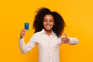 Happy woman holding credit card and thumbs up