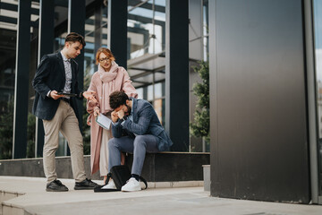 Two people comfort their business partner who is sitting alone and crying after a business loss, demonstrating empathy and support in a challenging moment.