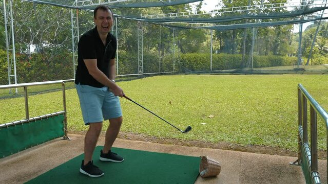 Focused golf player preparing for swing on practice range with lush greenery in background. Leisure activities and sports.