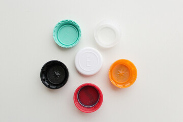 Top down view of of six color plastic bottle lids on grey background. Soda and juice bottle caps arranged on a pentagon shape.