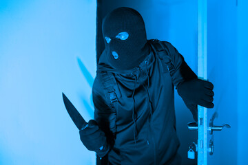 Armed burglar sneaking into a room at night