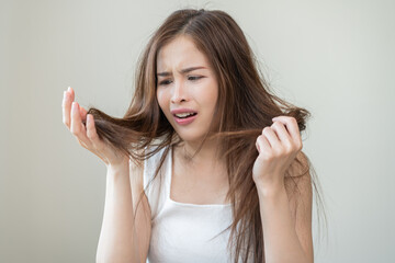 Damaged Hair, frustrated asian young woman, girl hand in holding splitting ends, messy unbrushed...