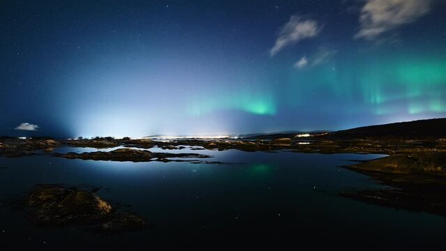 A night view towards the city of Bod&oslash; from the God&oslash;ynes passage. A distant aurora is dancing vividly, mirroring in a completely silent fjord.