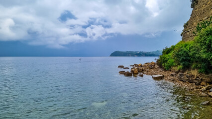 Fototapeta premium Panoramic view of idyllic coastline of Gulf of Piran, Adriatic Mediterranean Sea, Slovenia, Europe. Summer seaside vacation. Stroll along the tranquil stone beach of Fiesa. Shoreline Slovenian Istria