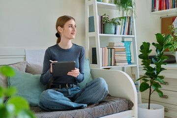 Young female teenager with digital tablet, stylus drawing illustrating sitting at home