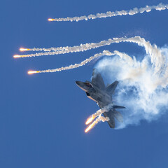 Epic view of a F-22 Raptor deploying flares in a turn, in smoke and in beautiful light