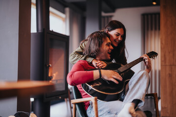 Intimate moment of a couple enjoying time together with a guitar by a cozy fireplace at home