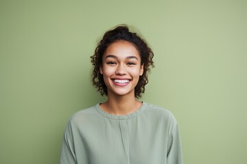 Fototapeta premium A woman with curly hair is smiling and wearing a green shirt