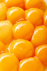 Close-up of several large yolks. The eggs are arranged in a way that creates a sense of depth and texture, with some eggs overlapping each other.