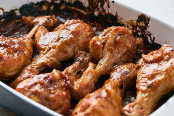 Chicken drumsticks baked in sauce in a baking dish close-up