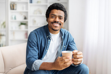 Man Sitting on a Couch Holding a Cup of Coffee