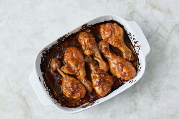 Chicken drumsticks baked in sauce in a baking dish close-up