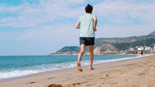A man runs along the seashore. With sea and mountains in the background. Healthy lifestyle