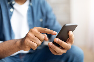 Black Man Using Smartphone Indoors With Focus on Hand