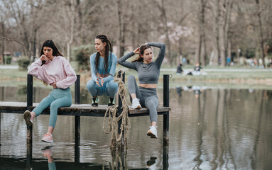 A candid moment capturing three young women as they unwind on a dock overlooking tranquil waters in...