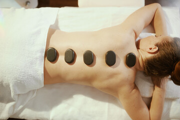 woman having hot stone massage and laying on massage table