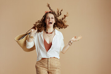smiling woman in blouse and shorts jumping on beige