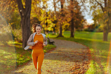 trendy female in fitness clothes in park running