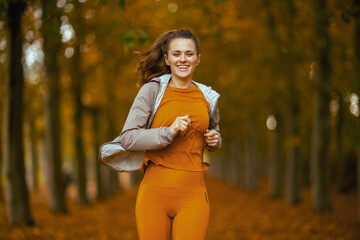 happy trendy woman in fitness clothes in park running - 779125061
