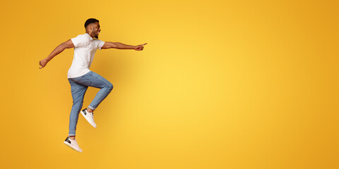 Excited african-american man jumping on orange background
