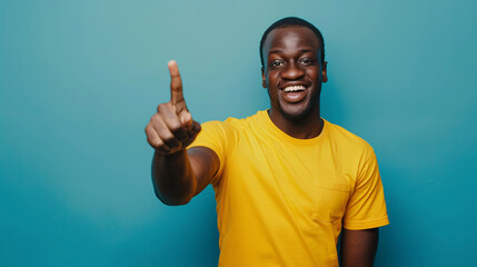 African man wearing yellow tshirt showing hand one finger up gesture against blue background
