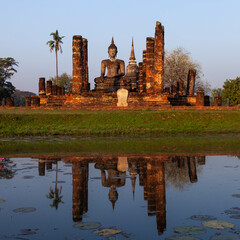 Sukhothai. Old buddhist temple ruins. Sitting Buddha statue nad pagoda reflecting in the pond at...