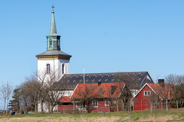 White wooden church with some red buildings